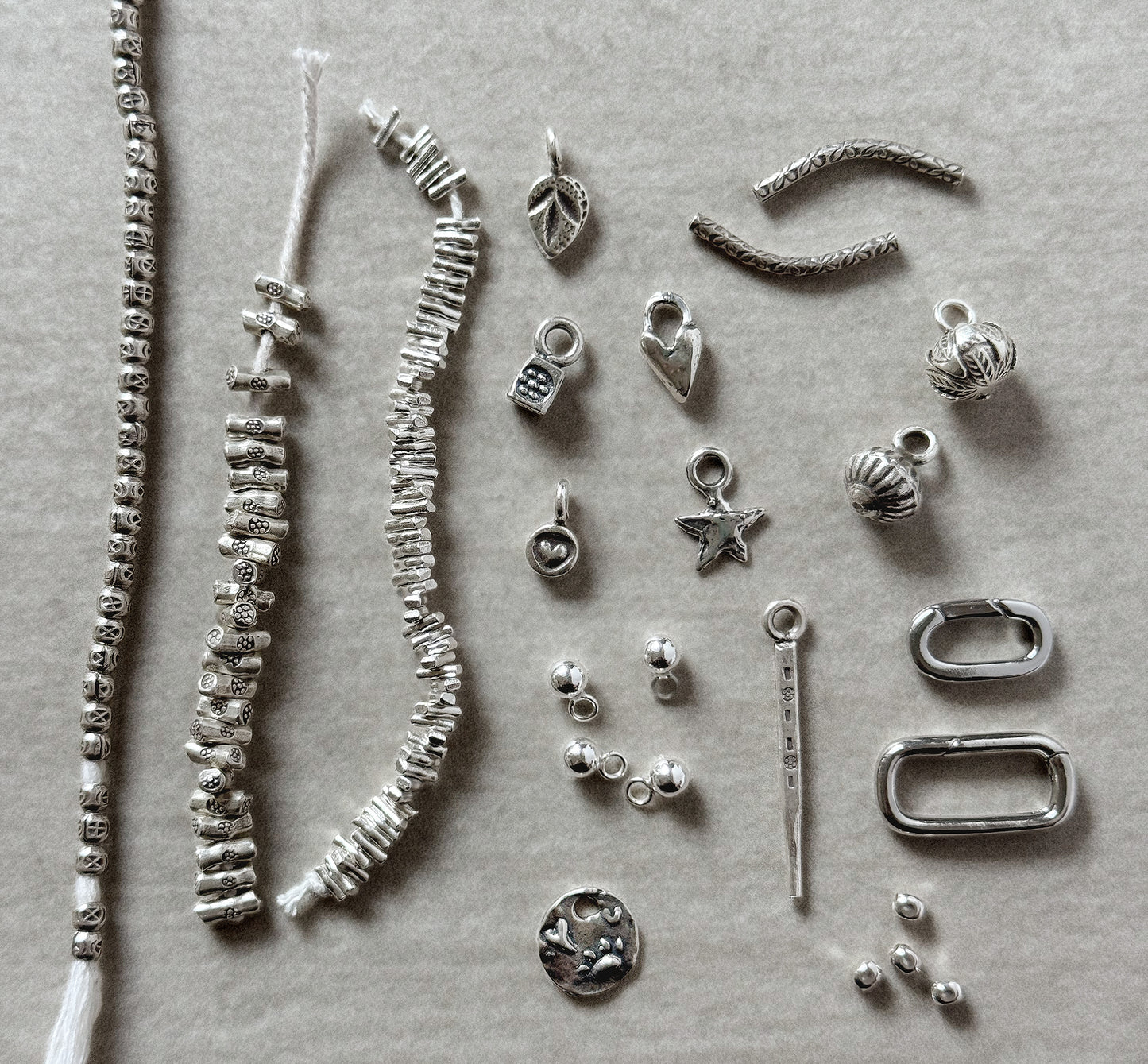 Collection of silver jewelry components on a gray background
