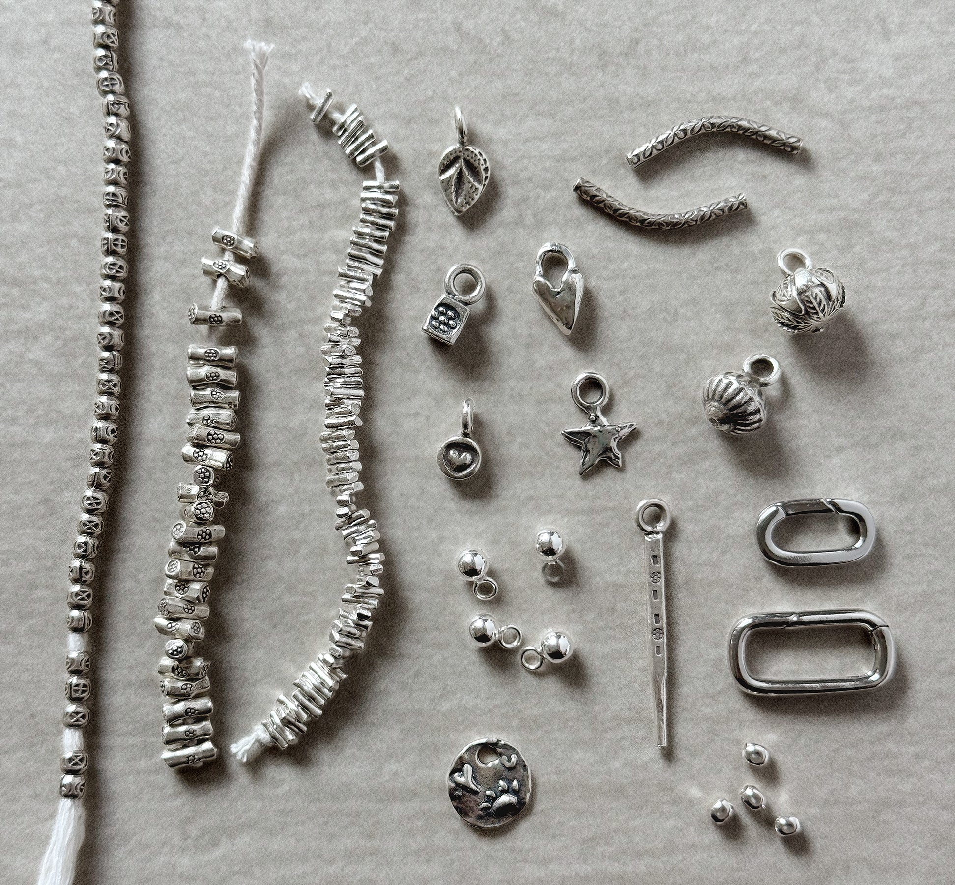 Collection of silver jewelry components on a gray background